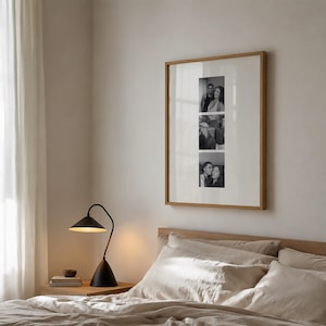 May include: A square wall art frame with a light wood finish containing a white mat and three vertical black and white photographs of people. The frame is displayed on a wall above a bed with beige bedding and a black desk lamp on a side table.