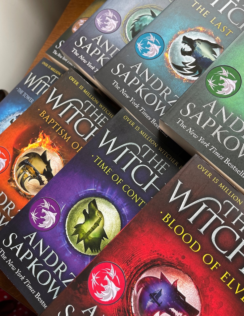 Op de afbeelding: Een verzameling paperbacks met een wolf op de omslag. De boeken zijn getiteld "The Witcher" en bevatten de naam van de auteur, Andrzej Sapkowski. De boeken zijn op elkaar gestapeld, met het bovenste boek "The Last Wish".