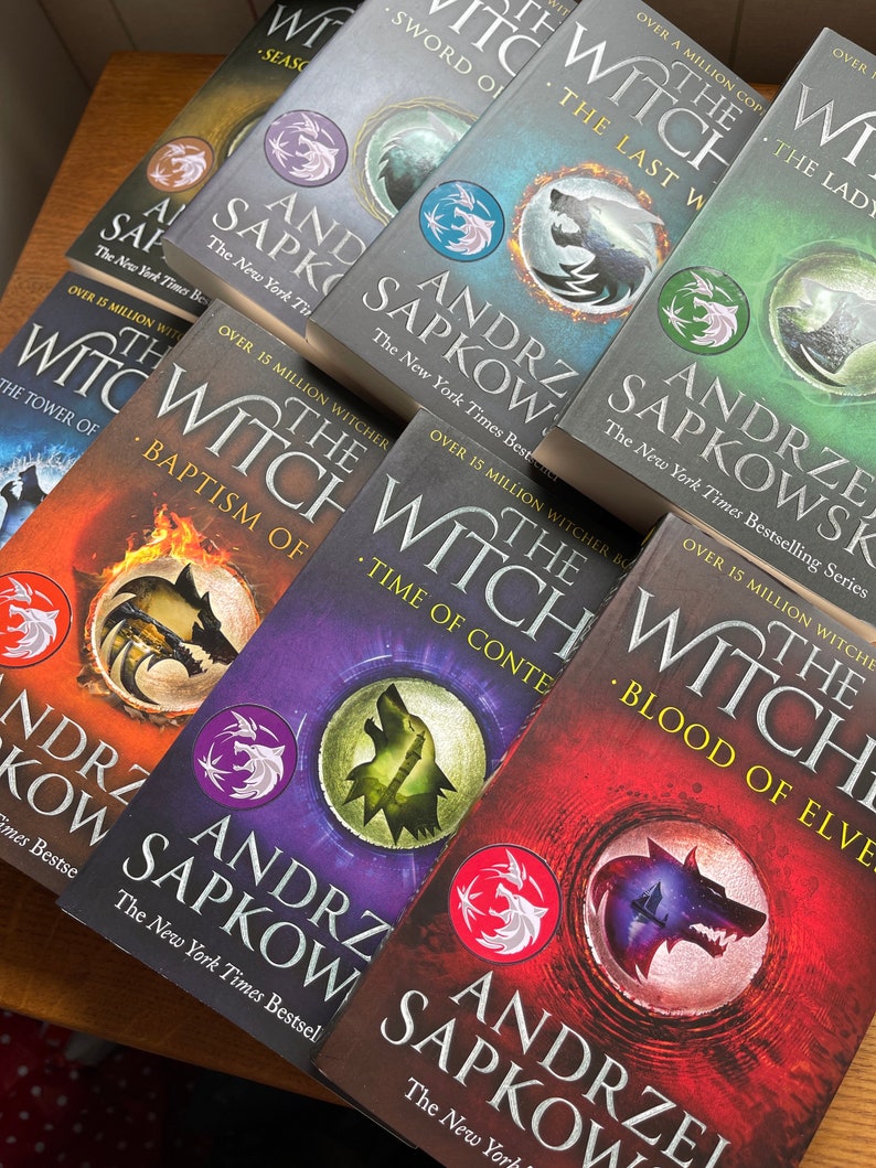 Op de afbeelding: Een stapel paperbacks met een fantasythema. De boeken zijn allemaal van Andrzej Sapkowski en tonen de Witcher-serie. De omslagen zijn een mix van rood, paars, blauw en zwart met wolvenbeelden.