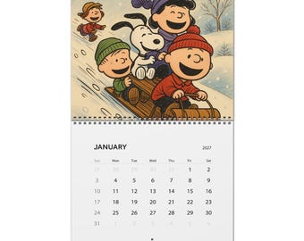 May include: A 2027 wall calendar for January featuring a colorful illustration of Snoopy and the Peanuts gang sledding down a snowy hill. The top section shows characters in winter hats riding a wooden sled, while the bottom displays the calendar grid.