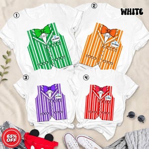 May include: Four white t-shirts featuring a graphic print of a striped waistcoat with a bow tie and a name tag that reads CAST MEMBER. The waistcoats are coloured green, orange, purple, and red. Each shirt has short sleeves and a crew neckline.