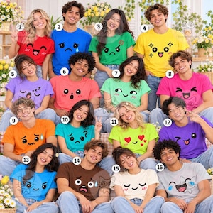 May include: A group of sixteen people wearing colorful t-shirts, each featuring a unique emoji-style facial expression, including happy, sad, angry, sleepy, surprised, and heart-eyed faces, arranged in a grid with numbered labels from one to sixteen.