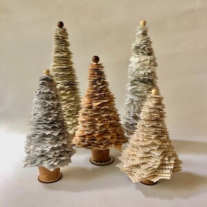 May include: Four decorative paper Christmas trees in various shades of brown and white. The trees are made of layered paper and have a rustic, vintage look.