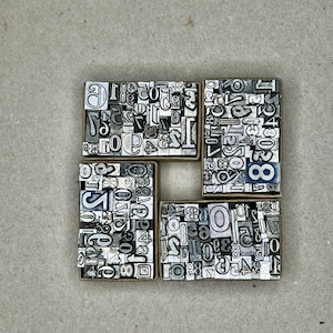 May include: Four small boxes filled with metal letterpress type. Each box contains a variety of numbers, with the numbers 0, 1, 2, 3, 4, 5, 6, 7, 8, and 9 visible in the image.