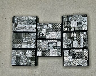May include: A set of six black trays filled with metal printing blocks. Each block features a different design, including geometric patterns, swirls, and floral motifs.