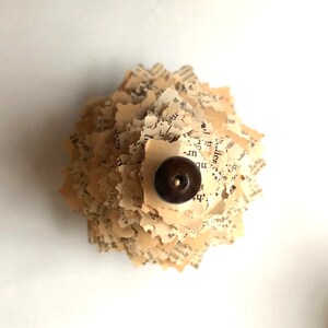 May include: A small, brown paper Christmas tree decoration with a brown wooden bead at the top.