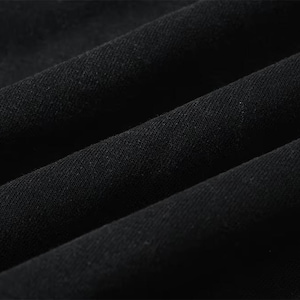 May include: Close-up of black fabric with visible texture and folds. The material appears to be a dark, solid color, possibly cotton or a similar textile. The image highlights the fabric's texture and the way it drapes.