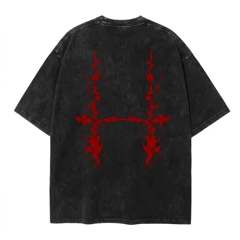 May include: A black, oversized t-shirt with a distressed, vintage wash. The back of the shirt features a bold, red graphic design. The graphic is a stylized, symmetrical design with a horizontal bar connecting two vertical flame-like elements.
