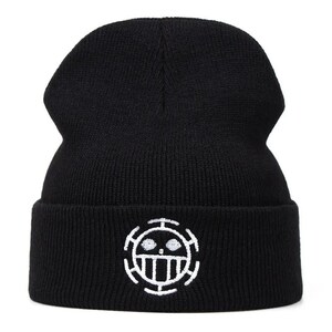 May include: Black knit beanie with a white embroidered emblem on the front. The emblem is a circular design with a skull and crossbones motif. The beanie is a classic, warm winter accessory.