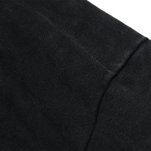 May include: Close-up of a black fabric, possibly a garment. The material appears to be textured, with visible seams. The image highlights the details of the textile, showcasing its color and construction.