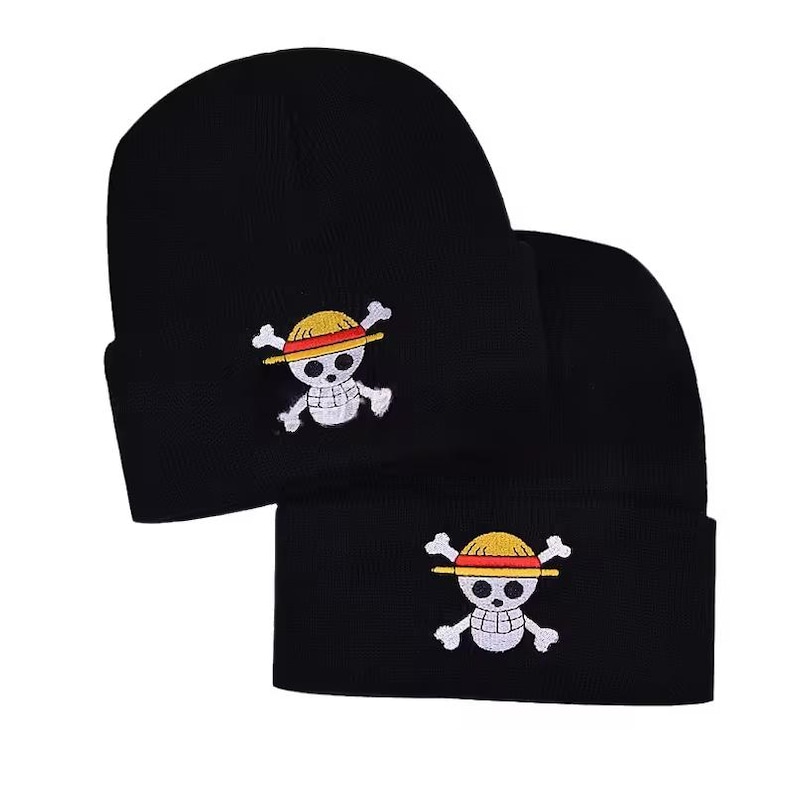 May include: Two black beanies with a white, yellow, and red embroidered skull and crossbones logo. The logo features a straw hat, a skull, and crossed bones. The beanies are made of a soft, knitted material.