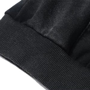 May include: Close-up of a black garment, possibly a sweatshirt or hoodie, with a ribbed cuff. The fabric appears to be a soft, textured material. The image highlights the details of the fabric and construction.