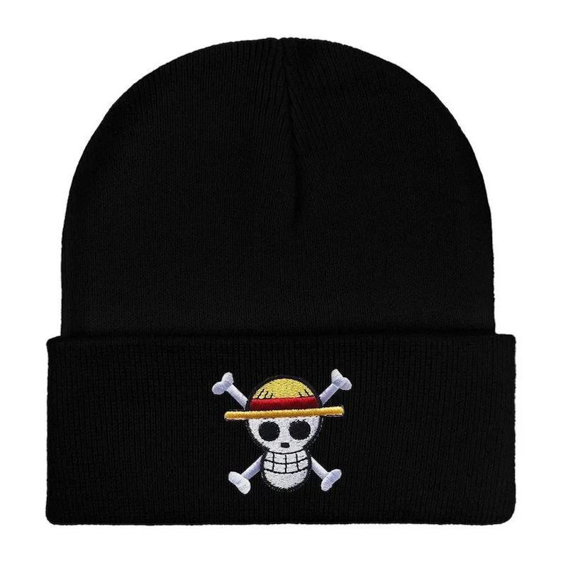May include: Black knit beanie featuring an embroidered Jolly Roger skull and crossbones logo with a straw hat design. The beanie is a classic, comfortable style, suitable for casual wear. The logo is in yellow, red, white, and black.
