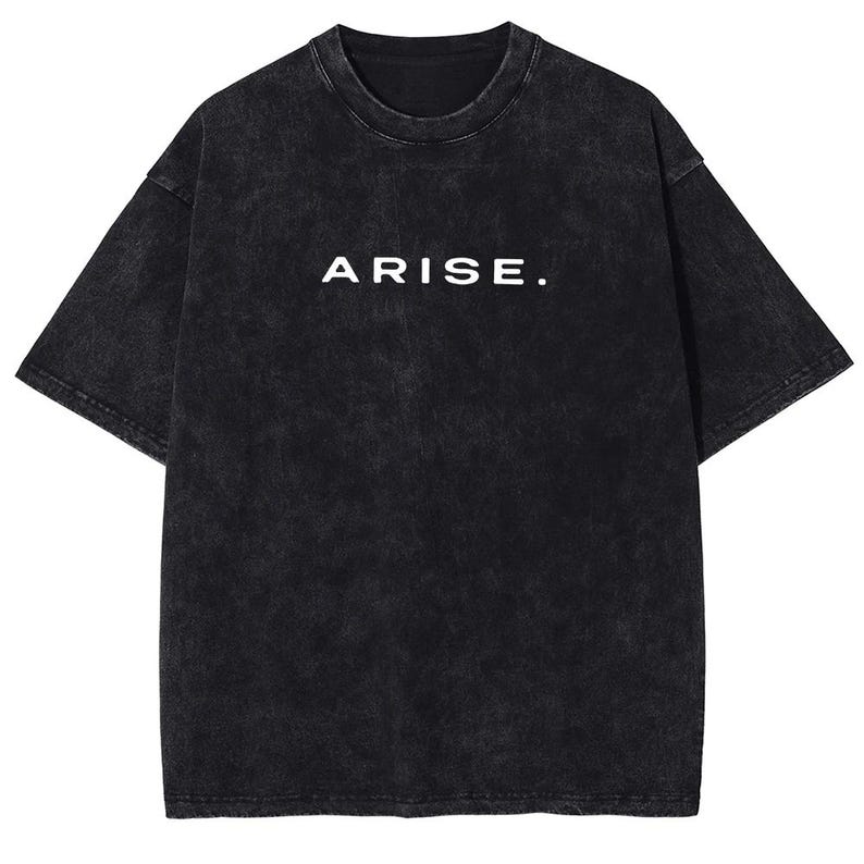 May include: Black, short-sleeved t-shirt with the word "ARISE." printed in white. The shirt has a faded, textured appearance. The t-shirt is a casual wear item.