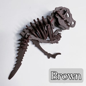 May include: A brown dinosaur skeleton puzzle, featuring a detailed design with visible ribs, skull, and tail. The puzzle is made of textured material and is displayed on a white surface. The word "Brown" is in a white font on a gray rectangle.