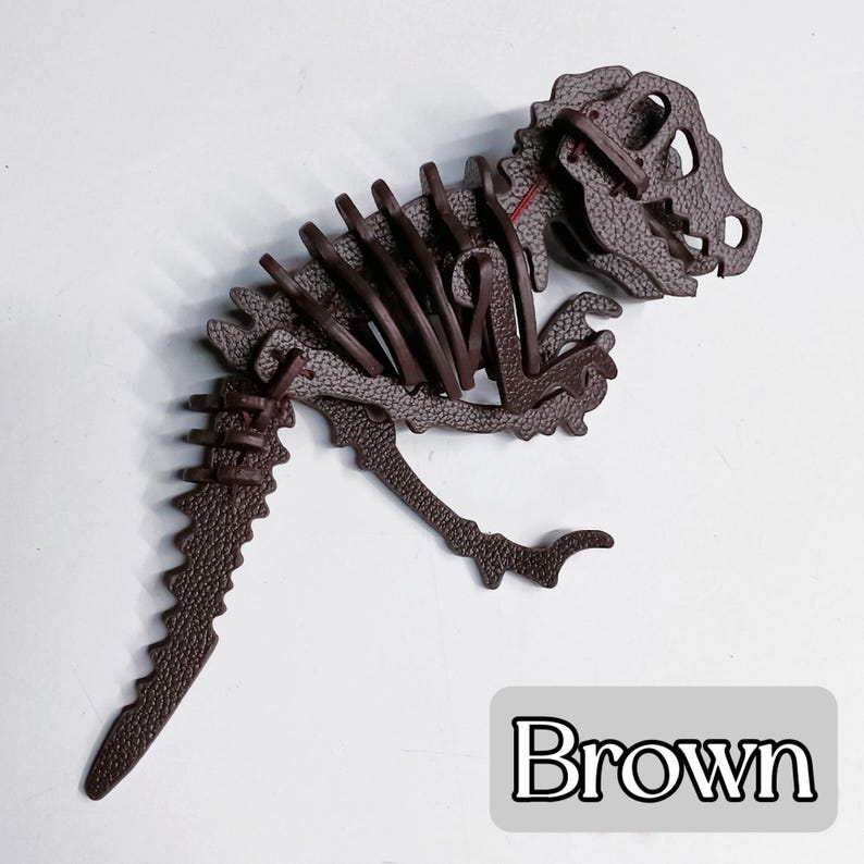 May include: A brown dinosaur skeleton puzzle, featuring a detailed design with visible ribs, skull, and tail. The puzzle is made of textured material and is displayed on a white surface. The word "Brown" is in a white font on a gray rectangle.