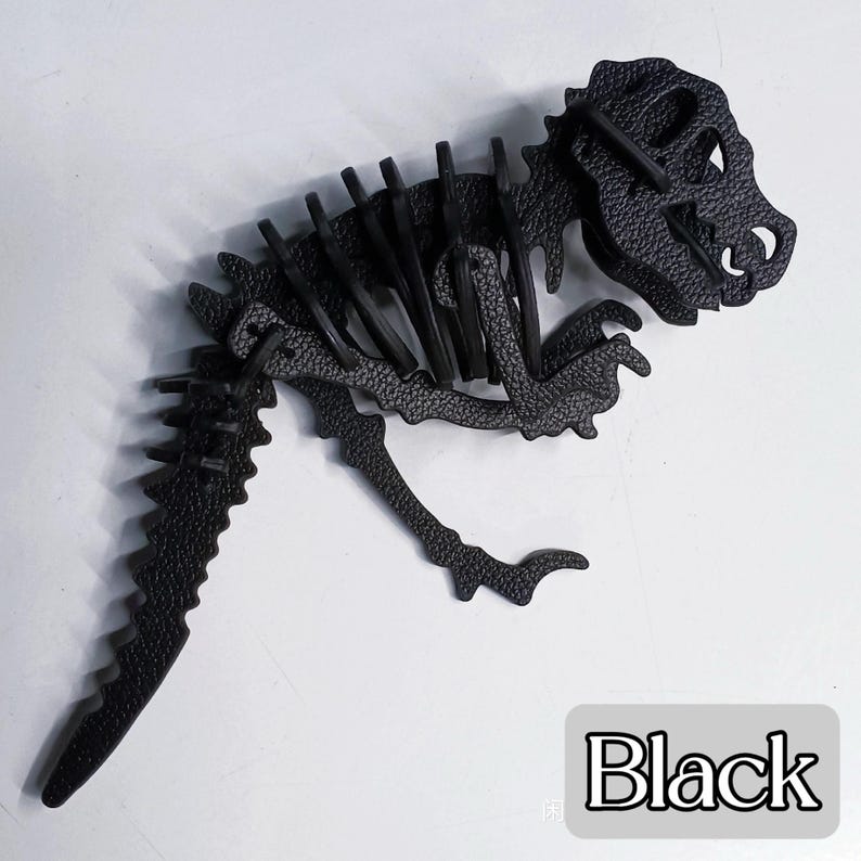 May include: A black dinosaur skeleton puzzle. The puzzle is made of textured material and features a detailed design of a Tyrannosaurus Rex. The word "Black" is in a white box at the bottom right.
