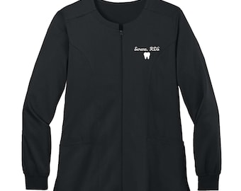 Könnte beinhalten: Schwarze, langärmelige Scrubs-Jacke mit Reißverschluss und zwei Taschen. Die Jacke ist mit einem weißen gestickten Zahn und dem Text "Serena, DDS" verziert.