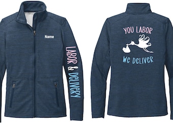 May include: Navy blue zip-up jacket with the text "Name" above the left chest. The left sleeve has the words "LABOR & DELIVERY" in a vertical gradient. The back features a stork graphic and the words "YOU LABOR, WE DELIVER".