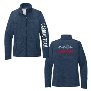 Peut inclure: Veste polaire bleu marine à fermeture éclair intégrale. La manche gauche porte l'inscription "CARDIAC TEAM" en blanc. Le dos de la veste présente un cœur et un graphique ECG avec l'inscription "CARDIAC TEAM" en rouge.