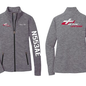 May include: Gray zippered jacket with a red and white logo on the front and back. The logo says "Air Evac Lifeteam". The jacket has a small American flag on the left sleeve and the text "N553AE" on the right sleeve. The jacket also has a name tag that says "Mary, RN".