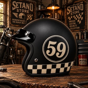 May include: A matte black open-face helmet featuring a white circular graphic with the number 59 in the centre. The lower edge of the helmet displays a white and black checkered pattern. A small black visor is attached to the front with silver snaps.