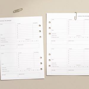 May include: Two white goal planner sheets with a paper clip on a beige background. Each sheet has sections for goals, actions, deadlines, and reflections. The text "GOAL PLANNER" is at the top of each sheet.