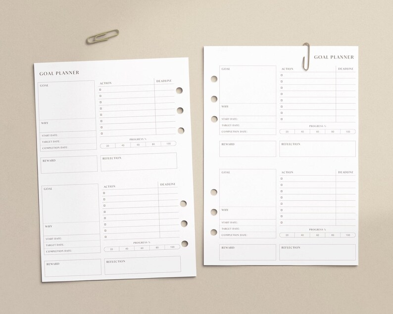 May include: Two white goal planner sheets with a paper clip on a beige background. Each sheet has sections for goals, actions, deadlines, and reflections. The text "GOAL PLANNER" is at the top of each sheet.