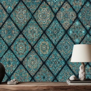 May include: A teal and gold patterned wallpaper with a repeating diamond design. A dark grey vase, a white lamp with a beige lampshade, and a stack of books sit on a wooden table in front of the wallpaper.