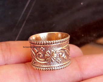 Könnte beinhalten: Nahaufnahme eines goldfarbenen Rings. Der Ring hat ein aufwendiges Blumendesign mit einem Perlenrand. Die Oberfläche des Rings ist mit einem Muster aus Blumen und Wirbeln verziert. Der Ring ist ein Schmuckstück.