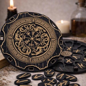 Può includere: Una tavola circolare in legno nero con un simbolo Vegvisir dorato al centro, circondato da motivi di draghi incisi e intrecci celtici. Un vassoio circolare abbinato con fessure intagliate contiene diverse piccole pietre runiche nere.