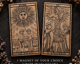 May include: Two rectangular magnets featuring black ink illustrations on a textured tan surface. The left magnet depicts the Sun tarot card labeled XVIII and LE SOLEIL. The right magnet shows the Lovers card labeled VI and L'AMOVREVX.