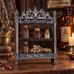 Può includere: Uno scaffale da speziale in legno nero a due ripiani, con decorazioni a volute bianche e le scritte "Apothecary" e "Potions Tonics Elixirs". Lo scaffale contiene boccette di vetro con tappi di sughero, erbe essiccate e un mazzetto di fiori.
