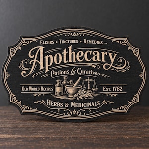 Könnte beinhalten: Ein schwarzes Holzschild mit einem verzierten, gewellten Rand und hellen, eingravierten Texten und Illustrationen. Das Schild trägt die Aufschriften Apothecary, Potions & Curatives, Elixirs, Tinctures, Remedies, Old World Recipes, Est. 1782 und Herbs & Medicinals.