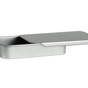 K&ouml;nnte beinhalten: Eine silberne Metalldose mit einem Scharnierdeckel. Der Deckel ist ge&ouml;ffnet und die Dose ist leer.
