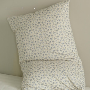 May include: A large, cream-colored pillow with a delicate floral pattern in light blue. The pillow is soft and appears to be made of a comfortable fabric, perfect for a bed or couch. The floral design adds a touch of elegance.