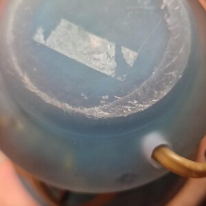 May include: A close-up of the bottom of a light blue glass object. The object has a rounded shape and a frosted appearance. The text "La Roche" is visible on the bottom of the object.