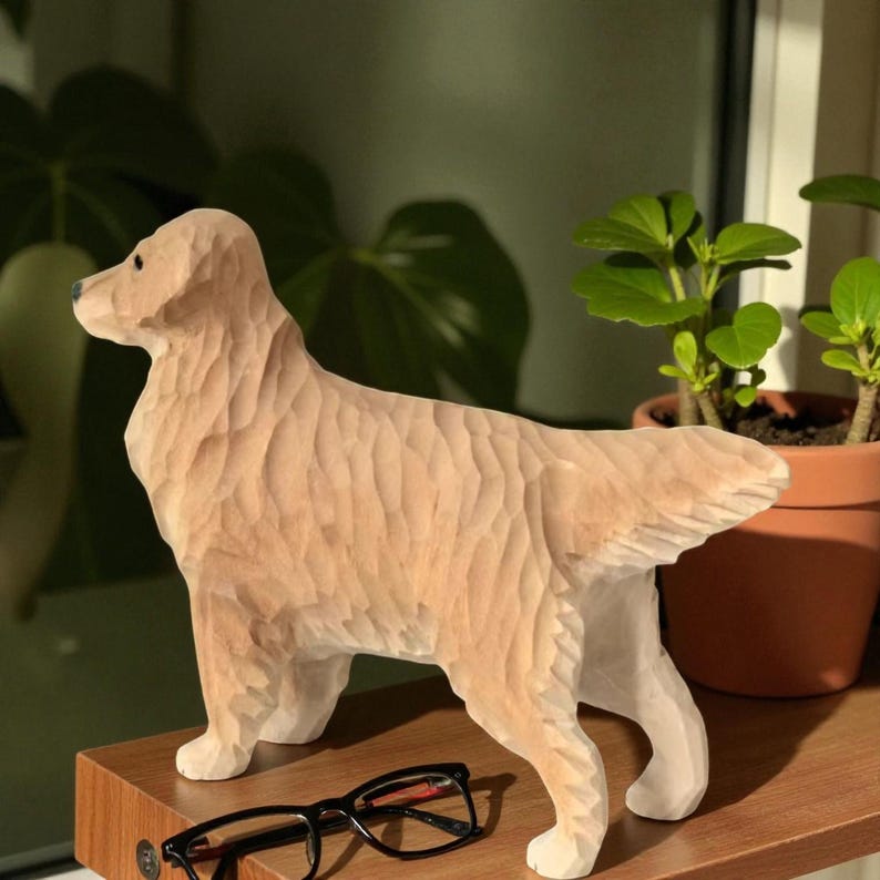 May include: A carved wooden sculpture of a Golden Retriever dog. The dog is light brown with a textured surface, standing on a wooden shelf. Black eyeglasses rest on the shelf in front of the dog. A potted plant is in the background.
