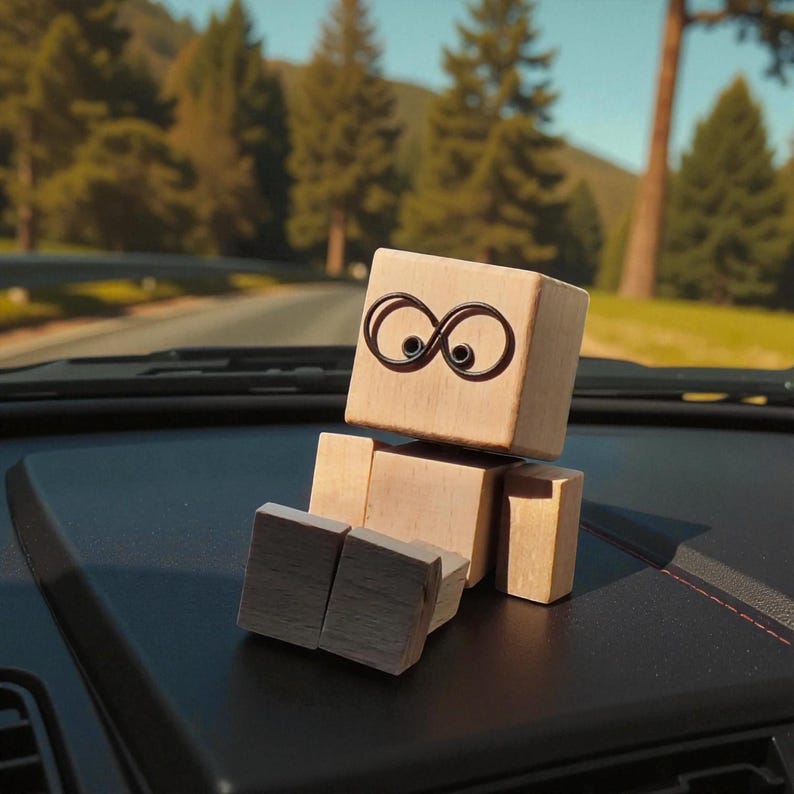 May include: A wooden block figure with a cube head and rectangular body and legs. The head has a pair of infinity symbol eyes. The figure is sitting on a black dashboard with a blurred background of a road and trees.