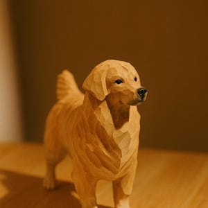 May include: A wooden sculpture of a Golden Retriever dog, standing on all fours. The dog is carved from light-colored wood, with detailed features including its fur, eyes, and nose. The sculpture is displayed on a wooden surface.
