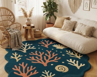 May include: A dark teal area rug with an irregular, wavy edge featuring a repeating pattern of light beige and coral-colored coral reef branches and spiral seashells. The rug has a textured surface and is placed on a light-colored wooden floor.