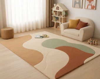 May include: A rectangular area rug featuring an abstract pattern of organic, flowing shapes in shades of cream, tan, terracotta, and sage green. The rug has a textured, plush surface and is positioned on a light-colored wooden floor in a room.