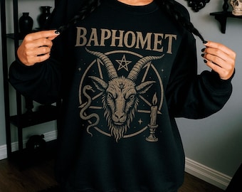 Peut inclure: Sweat-shirt noir avec le mot "BAPHOMET" en lettres beiges au-dessus d'une illustration de tête de chèvre dans un pentagramme. Le motif comprend un serpent, une bougie et des étoiles. La personne porte des lunettes et des cheveux noirs.
