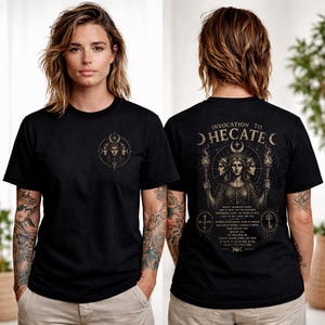 May include: Black t-shirt featuring a gold illustration of a woman with three faces, a crescent moon, and the text "Invocation to Hecate." The front of the shirt has a smaller version of the design. The shirt is short-sleeved.