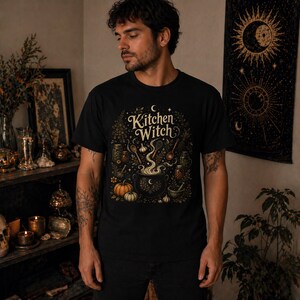 Kitchen Witch shirt featuring a vintage cottagecore folk magic design with herbal cauldron, mystical herbs, stars, and botanical details. Witchy unisex tee inspired by kitchen witchcraft, pagan spirituality, herbalism, and cozy mystical aesthetics. Perfect gift for witches, herbalists, cottagecore lovers, Wiccan fashion fans, and botanical magic enthusiasts.