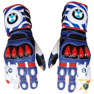Puede incluir: Par de guantes de moto azules, blancos y rojos con el logo de BMW. Los guantes tienen un diseño acolchado con detalles rojos en los nudillos y los dedos. La zona de la muñeca presenta un patrón de rayas azules y blancas.