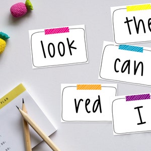 May include: Five white cards with black text and colorful tape on top. The words on the cards are "the", "look", "can", "red", and "I".