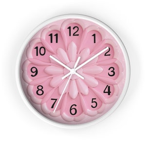 Könnte beinhalten: Eine runde Wanduhr in Rosa und Weiß mit Blumendesign und schwarzen Zahlen. Die Uhrzeiger sind weiß.