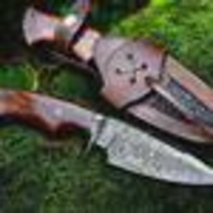 May include: A handcrafted hunting knife with a patterned blade and a wooden handle, presented with a leather sheath. The knife is approximately 9 inches long overall.