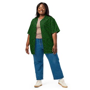 Puede incluir: Una camisa de manga corta con botones y un patr&oacute;n de c&oacute;digo binario en negro y verde, usada sobre una camiseta sin mangas color canela con jeans azules y zapatillas blancas. La camisa tiene cuello cl&aacute;sico y dobladillo recto digital.